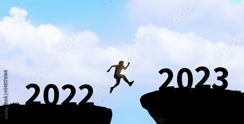 Happy new year 2023. Man silhouette jumping cliff from 2022 to 2023. start, goal, challenge.