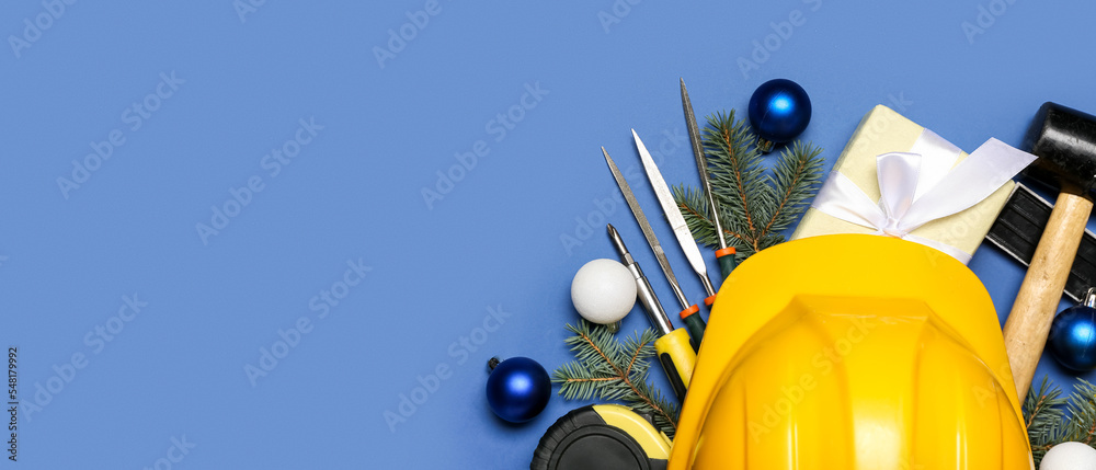 Obraz premium Builder's supplies with Christmas decor and gift on blue background with space for text