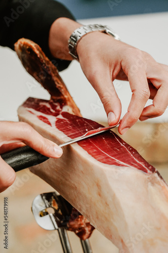 Profesional slicing Spanish jamon iberico (ham). Selective focus point