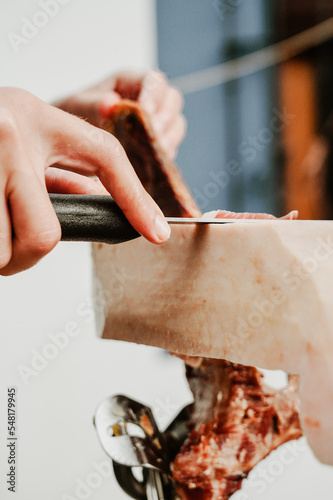 Profesional slicing Spanish jamon iberico (ham). Selective focus point