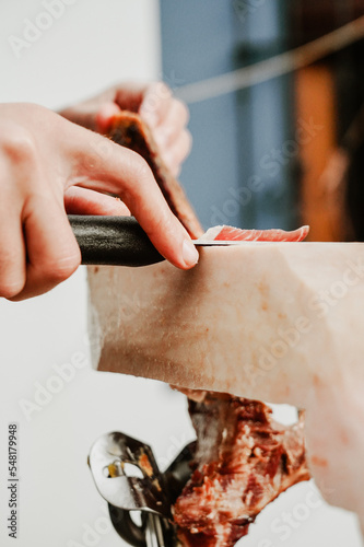 Profesional slicing Spanish jamon iberico (ham). Selective focus point