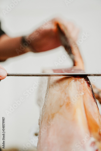 Profesional slicing Spanish jamon iberico (ham). Selective focus point