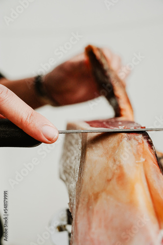 Profesional slicing Spanish jamon iberico (ham). Selective focus point