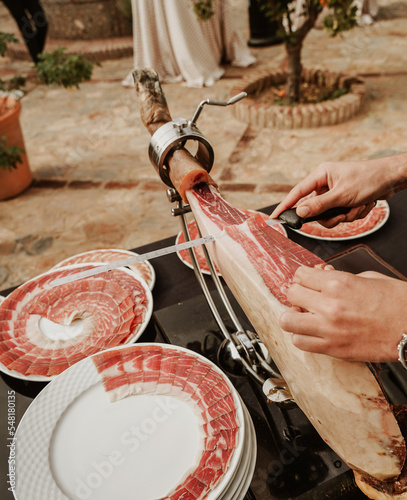Profesional slicing Spanish jamon iberico (ham). Selective focus point