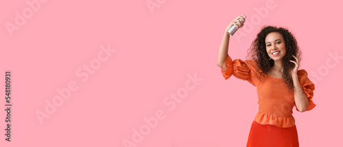 Stylish young African-American woman with hair spray on pink background with space for text