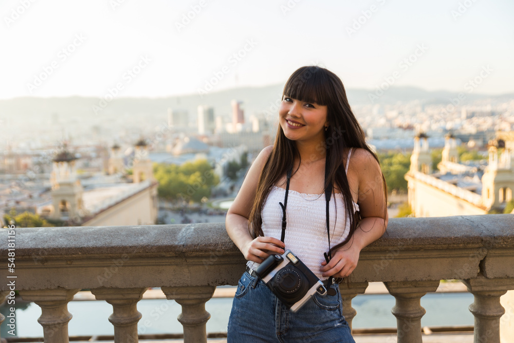 Young asian european woman doing sight seeing and smiling while she takes photos wih an old camera