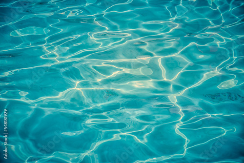 Azure clear water in a swimming pool with sun reflecting