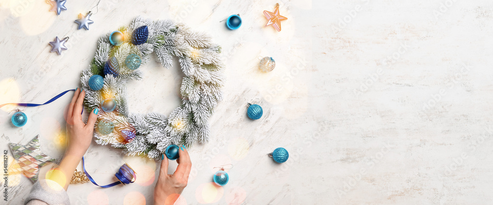 Hands of woman making beautiful Christmas wreath on light background with space for text