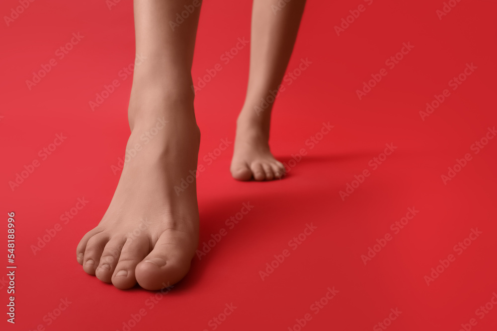Female bare feet on red background, closeup