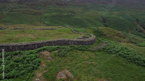 Aerial arc round perimeter of Hadknott Fort (Mediobogdum) in scenic mountainside photo