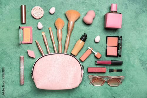 Pink bag with cosmetics and accessories on green background