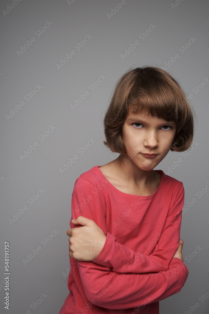 The little girl is angry, taking great offended. The hands are crossed. Gray isolated background. The little girl is angry, taking great offended. The hands are crossed. Gray isolated background.