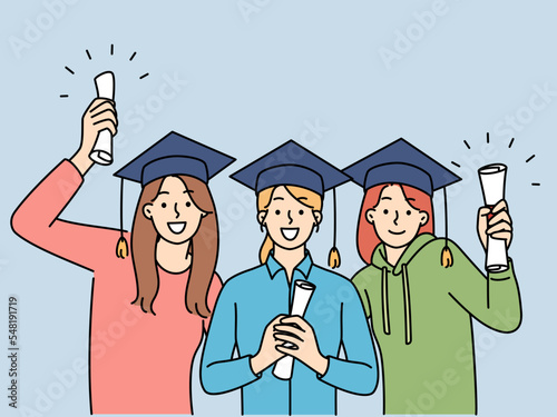 Happy girls holding graduation diplomas 