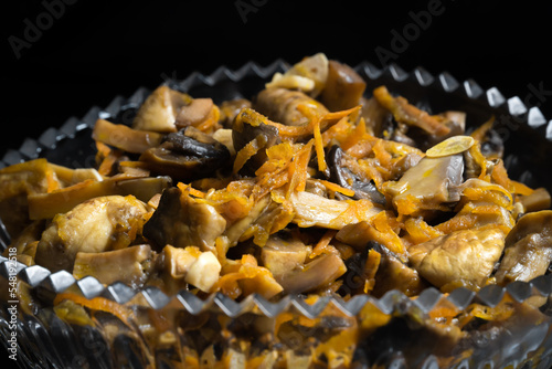Fototapeta Naklejka Na Ścianę i Meble -  Close-up of pickled mushrooms with carrots in a glass bowl on a black background. Snack, food