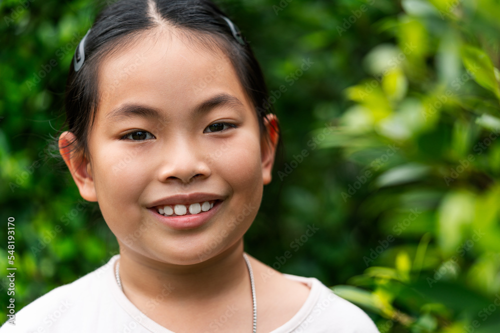 Portrait of Asian child girl in 8 to 9 years old, close up to face, smiling, looking at camera, outdoor image, blurred background of green plant garden. Portrait of Asian child girl in 8 to 9 years old, close up to face, smiling, looking at camera, outdoor image, blurred background of green plant garden.