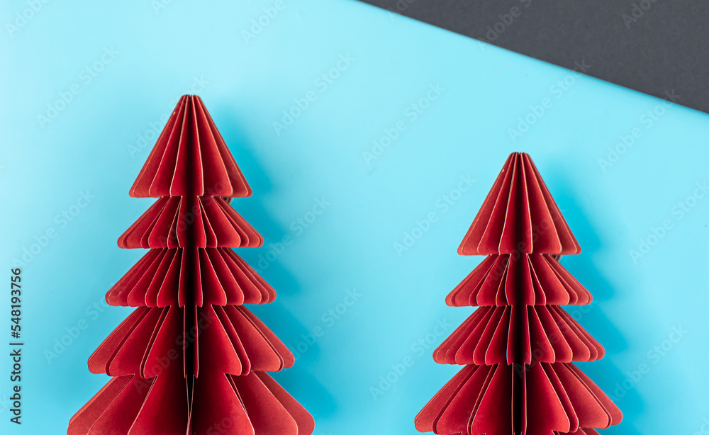 Two origami paper Christmas trees on a paper background, flat lay.