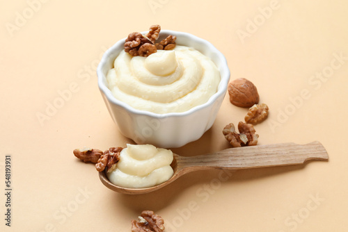 Ramekin of tasty vanilla pudding with walnuts on color background