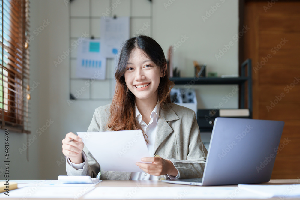 financial, Planning, Marketing and Accounting, portrait of Asian employee checking financial statements using documents and computer laptop at work financial, Planning, Marketing and Accounting, portrait of Asian employee checking financial statements using documents and computer laptop at work