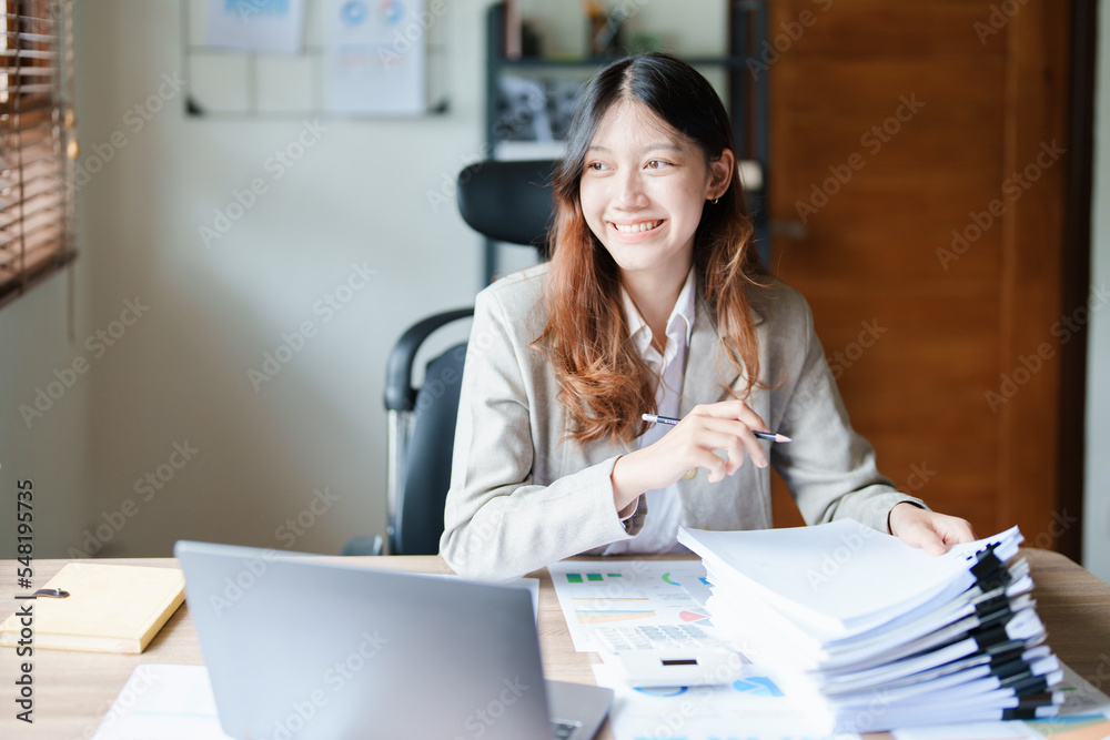 financial, Planning, Marketing and Accounting, portrait of Asian employee checking financial statements using documents and computer laptop at work financial, Planning, Marketing and Accounting, portrait of Asian employee checking financial statements using documents and computer laptop at work