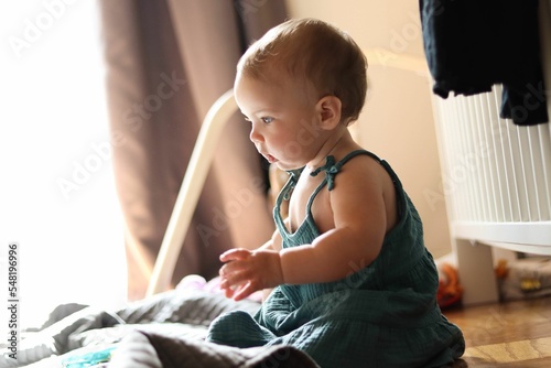 10 month old Caucasian baby girl playing in her room wearing a blue-green dress photo