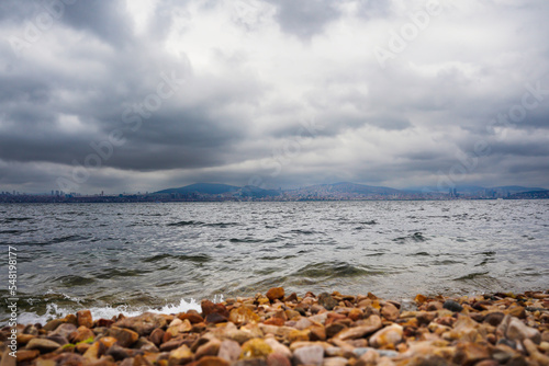 rocks , sea , cloudy sky , and mountains in the background 