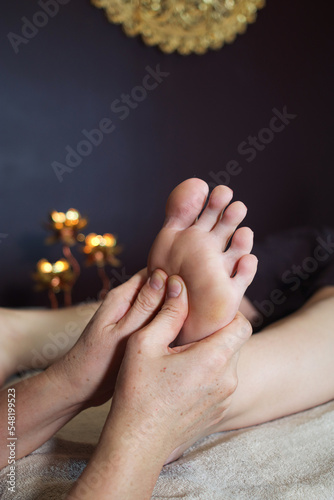 Feet with hands of therapist pressing thumbs on it.  It's a Thai traditional foot massage for tension reliving, it is also known for its work on energy lines also called 