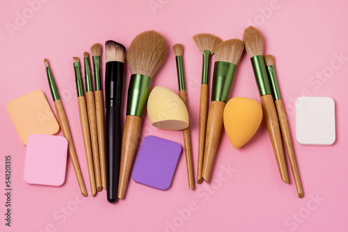 Set of Makeup Brushes and Sponges Beauty Blenders Puff Sponges and Variety of Brush on Pink Background Top View