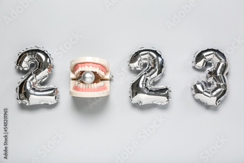Figure 2023 made of balloons with jaw model and Christmas ball on grey background