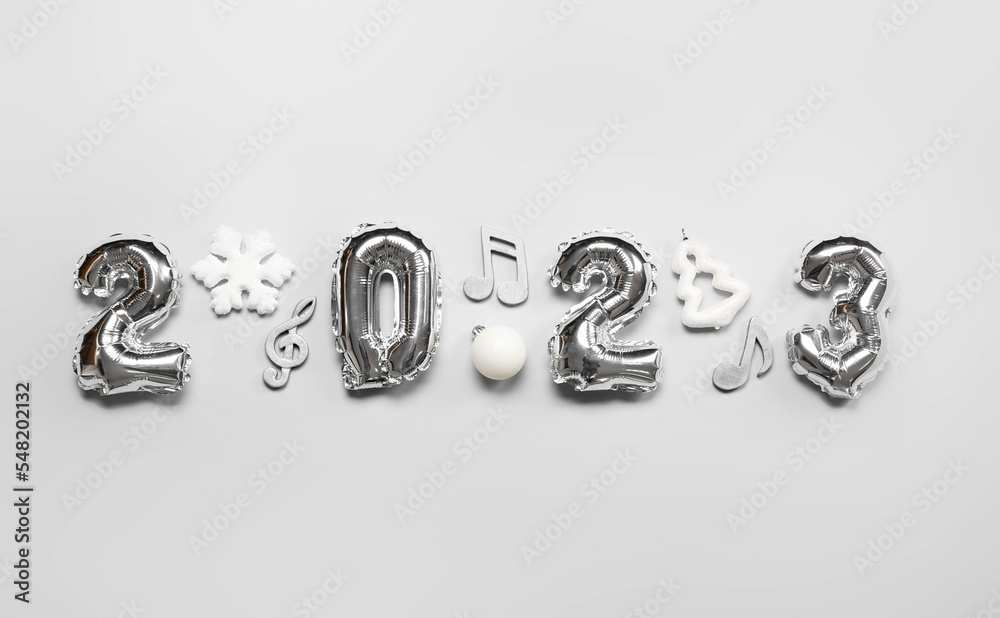 Figure 2023 made of balloons with Christmas decor and note signs on grey background Figure 2023 made of balloons with Christmas decor and note signs on grey background