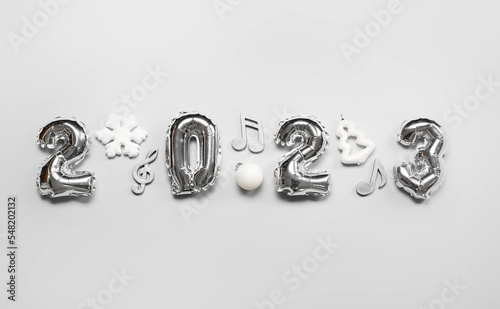 Fototapeta Naklejka Na Ścianę i Meble -  Figure 2023 made of balloons with Christmas decor and note signs on grey background