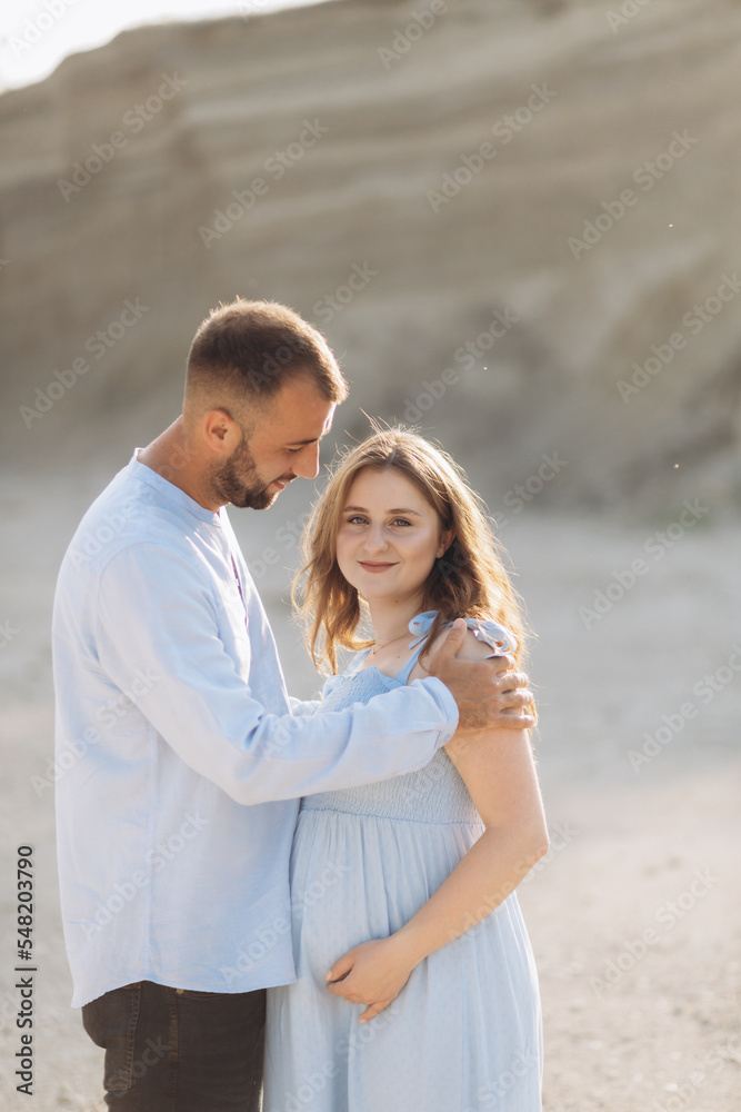 Portrait of a lovely couple standing together on the greenfield. Happy couple expecting a baby, young family concept Portrait of a lovely couple standing together on the greenfield. Happy couple expecting a baby, young family concept