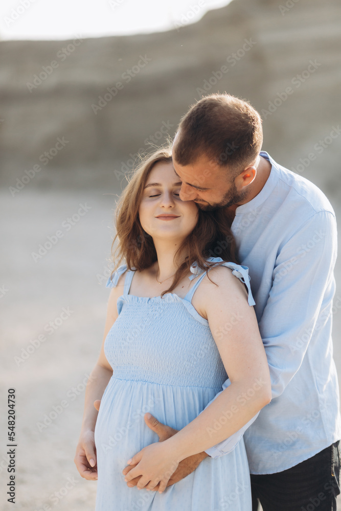 Portrait of a lovely couple standing together on the greenfield. Happy couple expecting a baby, young family concept