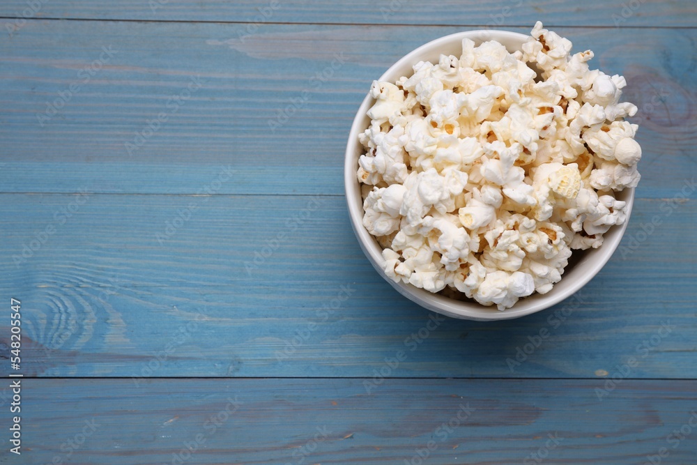 Tasty popcorn on light blue wooden table, top view. Space for text Tasty popcorn on light blue wooden table, top view. Space for text