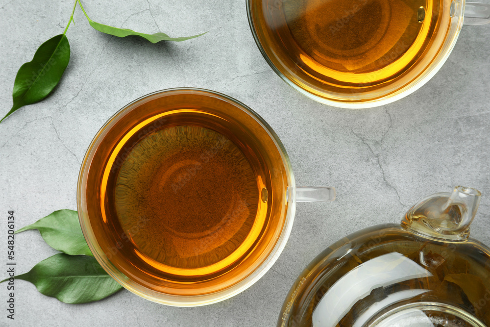 Fresh green tea in glass cups and leaves on grey table, flat lay Fresh green tea in glass cups and leaves on grey table, flat lay