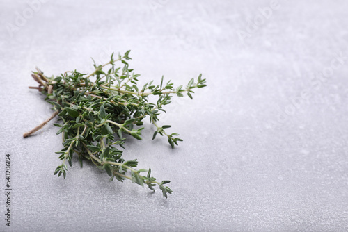 Bunch of fresh thyme on light grey table, space for text
