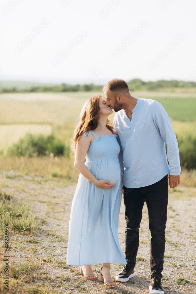 Portrait of a lovely couple standing together on the greenfield. Happy couple expecting a baby, young family concept Portrait of a lovely couple standing together on the greenfield. Happy couple expecting a baby, young family concept