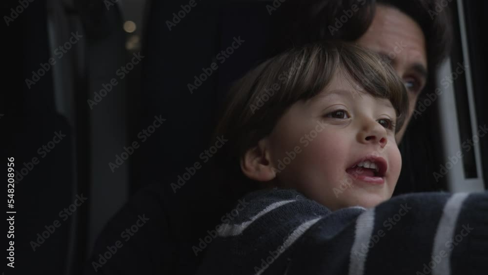 Child seated on father lap traveling by train. Closeup faces of kid and child together Child seated on father lap traveling by train. Closeup faces of kid and child together