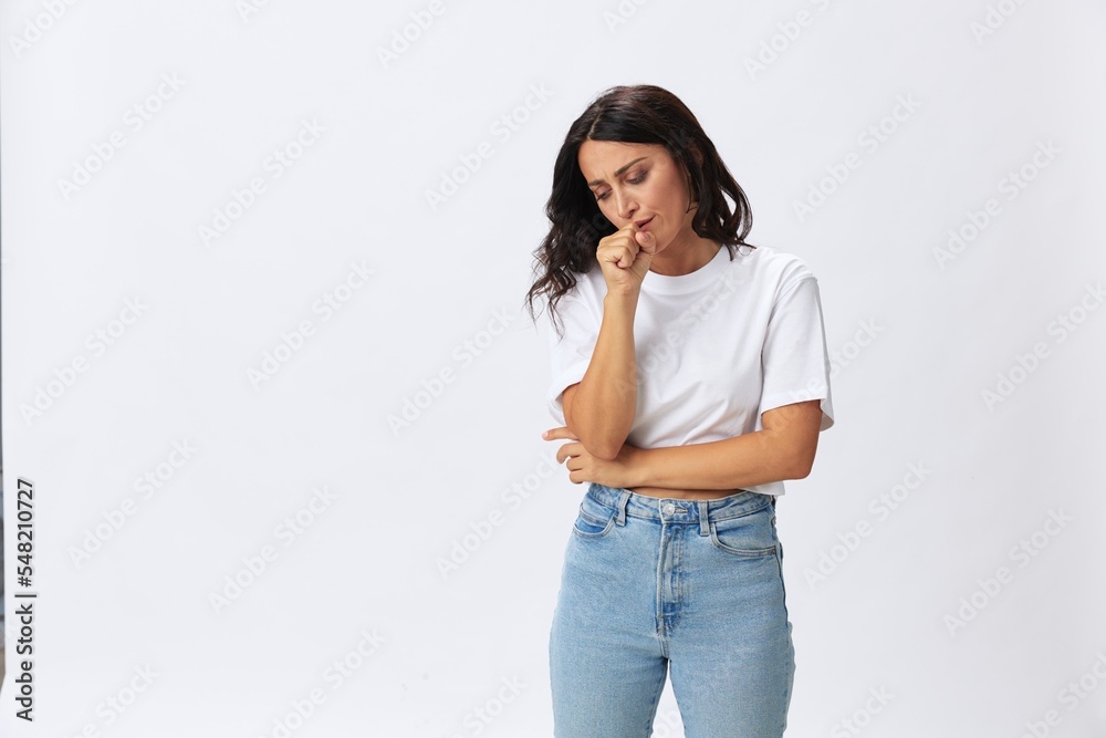 Woman sore throat and inflammation of the ligaments with a cold, a woman in a white t-shirt and jeans on a white background, copy space Woman sore throat and inflammation of the ligaments with a cold, a woman in a white t-shirt and jeans on a white background, copy space