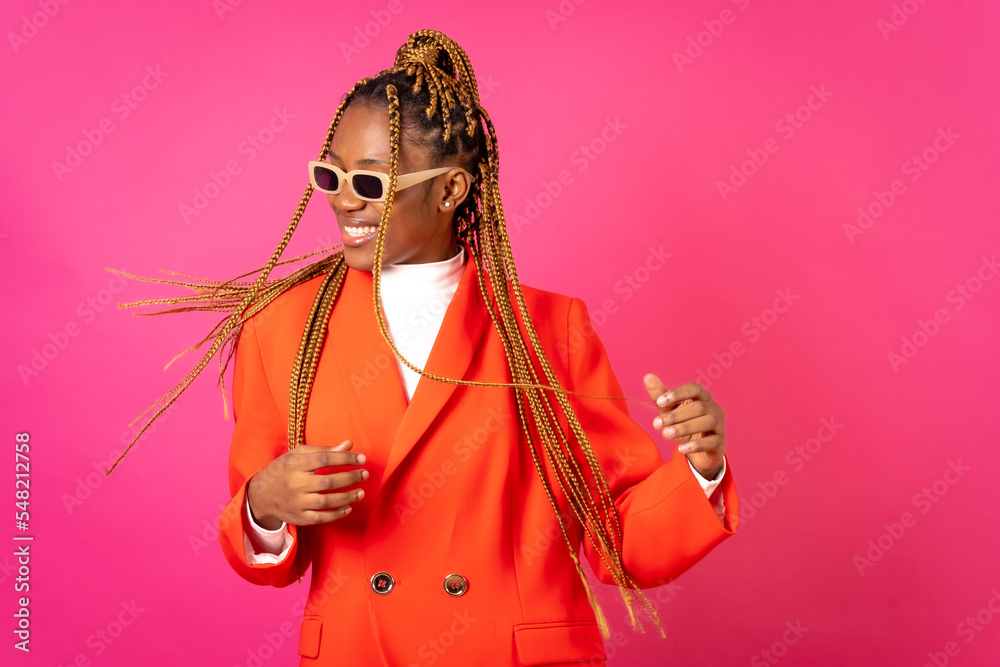 African young woman with braids on a pink background, in a red outfit having fun African young woman with braids on a pink background, in a red outfit having fun