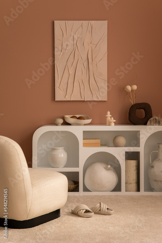Interior design of living room interior with mock up poster frame, modern commode, beige rug, slippers, bowl with coconut, candles, apple sculpture and personal accessories. Home decor. Template.