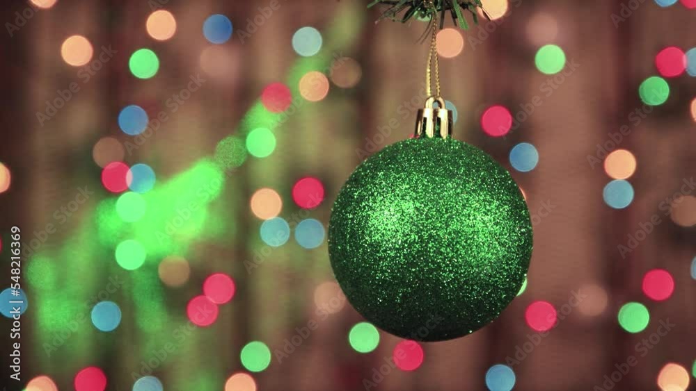 Close-up of green Christmas balls on a background of twinkling lights. New Year's multi-colored garlands in defocus. Holiday card with bokeh. Abstract background for captions and text. UHD 4K. Close-up of green Christmas balls on a background of twinkling lights. New Year's multi-colored garlands in defocus. Holiday card with bokeh. Abstract background for captions and text. UHD 4K.