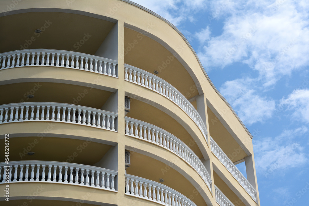 Obraz premium Exterior of beautiful building with balconies against blue sky, low angle view