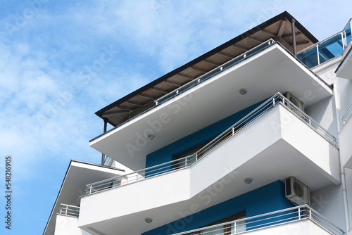 Fotografering Exterior of beautiful building with balconies against blue sky, low angle view