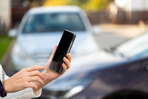 woman with smartphone standing next to the car, using mobile app for paying, car lock or Internet