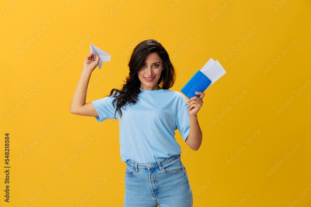 Traveler woman with yellow suitcase, passport and ticket in hand, paper plane, blue t-shirt and jeans on yellow background tourist, travel happiness, glasses, copy space Traveler woman with yellow suitcase, passport and ticket in hand, paper plane, blue t-shirt and jeans on yellow background tourist, travel happiness, glasses, copy space