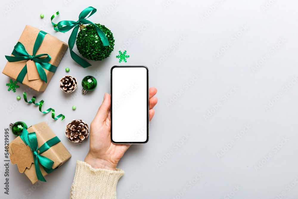 christmas mockup with space for text. christmas advertising, app template. hand holding phone with empty screen on table background. Happy New Year and Xmas Flat lay - obrazy, fototapety, plakaty 