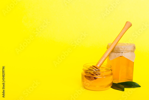 Honey in jar with leaves and honey dipper on colored background top view with copy text