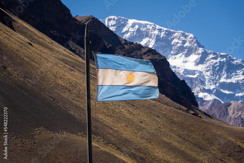 Foto Argentine flag fluttering in the wind, behind the Aconcagua hill in Mendoza Arge
