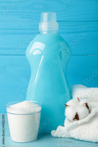 Eco washing concept. Laundry detergent, cotton flowers and blue towel on grey background, copy space. Vertical photo