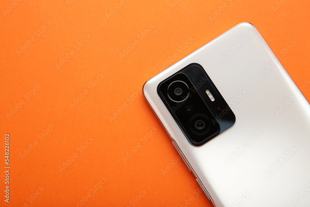 Fototapeta premium White smartphone on orange background. Top view